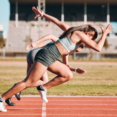 Action, sports and athlete running sprint in competition or fitness game or training for energy wellness on track. Race, stadium and athletic people or runner exercise, speed and workout performance.